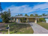Cute yellow house with a carport and well-manicured lawn at 2480 Del Rio Way, Dunedin, FL 34698