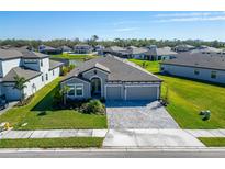 Single-Gathering home with gray exterior, three-car garage, and landscaped lawn at 9152 Warm Springs Cir, Parrish, FL 34219