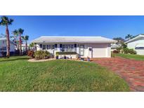 White single story home with landscaped lawn, brick pavers, and palm trees at 9156 142Nd St, Seminole, FL 33776