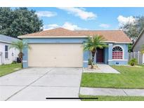 Cute blue house with a two-car garage and palm trees at 12908 Brant Tree Dr, Riverview, FL 33579