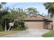 Tan colored exterior home with a two-car garage and manicured landscaping at 7108 Saint Andrews Ln, Sarasota, FL 34243