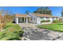 White single story home with carport and mature landscaping at 2243 Greenwich Dr, Sun City Center, FL 33573