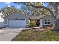 One-story home with attached garage, landscaping, and a large tree at 412 Arlington E Ave, Oldsmar, FL 34677