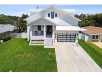 Two-story white house with metal roof, gray driveway, and landscaped lawn at 4329 Helena Ne St, St Petersburg, FL 33703