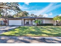 Tan house with white garage door and green lawn at 1206 Meadowcrest Dr, Valrico, FL 33594