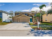 Two-story house with a three-car garage and landscaped yard at 15815 Muirfield Dr, Odessa, FL 33556