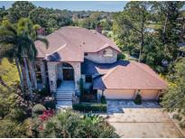 Brick house with two-car garage, stone driveway, and lush landscaping at 10534 Indian Hills Ct, Seminole, FL 33777