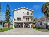 Two-story house with gray siding, multiple balconies, and a carport at 140 142Nd E Ave, Madeira Beach, FL 33708