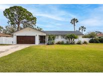 White single story home with a brown door and lush green lawn at 5321 Dover Ne St, St Petersburg, FL 33703
