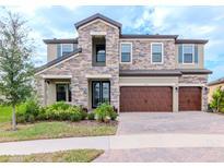 Two-story house with stone exterior, three-car garage, and landscaped front yard at 12795 Fisherville Way, Riverview, FL 33579