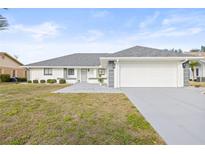 White single-story house with gray roof, two-car garage, and landscaped front yard at 2024 N Pebble Beach Blvd, Sun City Center, FL 33573
