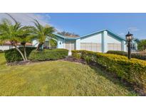 Light blue house with palm trees and well-manicured hedges at 2618 Locksley St, Sun City Center, FL 33573