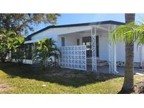 White single-wide mobile home with covered porch and landscaped yard at 27466 Us Highway 19 N # 97, Clearwater, FL 33761