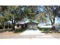 Tan one-story house with a two-car garage and mature landscaping at 36150 Pine Bluff Loop, Dade City, FL 33525
