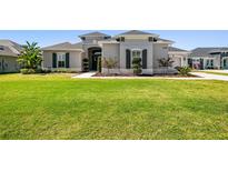 Single-story home with gray exterior, landscaping, and a large yard at 5226 Lake Venice Dr, Wimauma, FL 33598