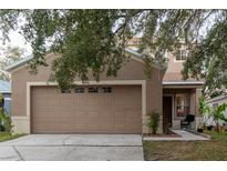 Two-story house with tan exterior, attached garage, and landscaping at 10438 Blackmore Dr, Tampa, FL 33647