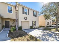 Tan two-story townhome with brown accents, two-car garage, and landscaping at 12816 Buffalo Run Dr, Gibsonton, FL 33534