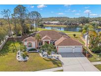 Single-story home with a two-car garage, mature landscaping, and a pond view at 3702 Gaviota Dr, Ruskin, FL 33573