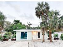 Cute bungalow with a light teal exterior, palm trees, and a white-washed front porch at 690 Fox St, Longboat Key, FL 34228