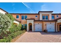 Tan two-story townhome with two-car garage and landscaped front at 10059 Crooked Creek Dr # 102, Venice, FL 34293