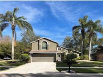 Two-story house with a two-car garage and palm trees in the front yard at 4047 Eagle Cove West Dr, Palm Harbor, FL 34685