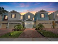 Three-story townhouses with attached garages, brick pavers, and landscaping at 4402 Sailplane Ct, Wesley Chapel, FL 33545