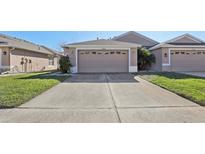 Front view of a beige house with a two-car garage and grassy area at 31447 Shaker Cir, Wesley Chapel, FL 33543