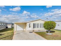 Single-wide manufactured home with attached garage and carport, featuring a well-manicured lawn at 37539 Gill Ave, Zephyrhills, FL 33541