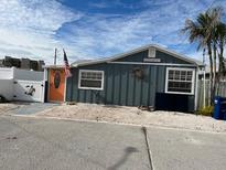 Charming beach cottage with gray siding, orange door, and landscaped yard at 13708 Salem St, Madeira Beach, FL 33708