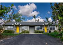 Duplex with gray siding, yellow doors, and a paved driveway at 1637 82Nd Street E Ct, Palmetto, FL 34221