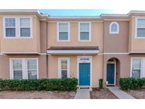 Tan two-story townhome with teal door, landscaping, and two parking spots at 8951 Walnut Gable Ct, Riverview, FL 33578
