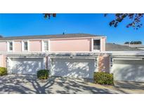 Rear view of building, showing three attached garages and light pink exterior at 11824 Cypress Crest Cir, Tampa, FL 33626