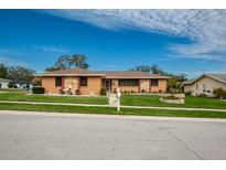 Single story home with stone accents, landscaped yard, and a two car garage at 153 Sunward Ave, Palm Harbor, FL 34684