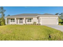 One-story home with light beige exterior, dark gray roof, and a two-car garage at 7258 Bridgeport Ln, Englewood, FL 34224