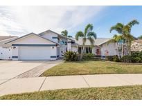 White house with blue accents, two-car garage, and landscaped yard at 1028 Wyndham Way, Safety Harbor, FL 34695