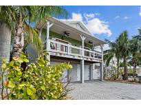 Elevated home with two-car garage, front porch, and tropical landscaping at 12116 Lagoon Ln, Treasure Island, FL 33706