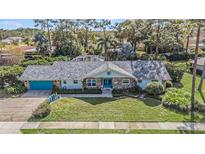 Exterior of charming ranch home with turquoise garage doors, stone accents, and lush landscaping at 2241 Toniwood Ln, Palm Harbor, FL 34685
