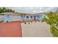 Cute light blue house with red door, white garage door, and well-manicured landscaping at 4415 60Th Street W Ct, Bradenton, FL 34210