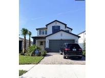 Two-story home with gray garage door and landscaping at 4861 Tramanto Ln, Wesley Chapel, FL 33543