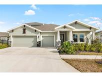 Two-story house with three car garage, stone accents and landscaping at 6189 Hidden Branch Dr, Apollo Beach, FL 33572