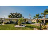 Inviting yellow house with a landscaped lawn and palm trees at 7820 Wallaba Ln, New Port Richey, FL 34653