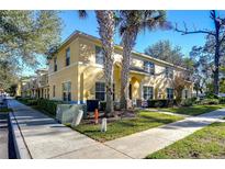 Tan two-story townhome with palm trees and manicured landscaping at 37650 Aaralyn Rd, Zephyrhills, FL 33542