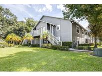 Gray condo building with exterior stairs, landscaping, and grassy yard at 11847 Skylake Pl # D, Tampa, FL 33617