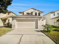 Two-story house with beige exterior, attached garage, and landscaping at 32328 Fish Hook Loop, Wesley Chapel, FL 33545