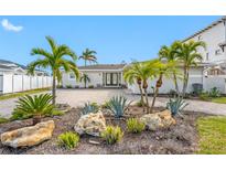 A waterfront home with palm trees and a paved driveway at 65 Dolphin Dr, Treasure Island, FL 33706