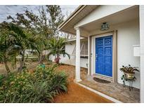 Inviting home exterior featuring a vibrant blue front door and well-manicured landscaping at 1295 56Th N St, St Petersburg, FL 33710