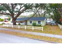 Light green house with white fence, large oak tree, and a boat in the yard at 9507 N 42Nd St, Tampa, FL 33617