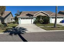 Light teal home with white garage door and landscaping at 1743 Arabian Ln, Palm Harbor, FL 34685