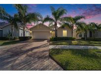 House exterior at dusk, featuring a two-car garage and palm trees at 1861 Pacific Dunes Dr, Sun City Center, FL 33573