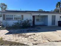 Ranch-style home with solar panels and a paved driveway at 246 94Th N Ave, St Petersburg, FL 33702
